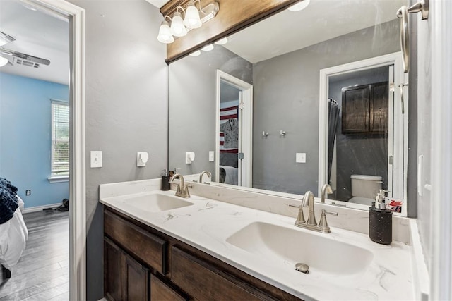 12116 NW 137th St, Piedmont, OK 73078 - ensuite bathroom featuring toilet, wood finished floors, double vanity, and baseboards