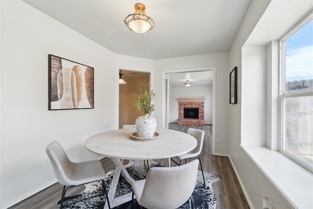 2013 Cedar Meadow Ln, Edmond, OK 73003 - dining area featuring a fireplace, dark wood-style floors, and baseboards