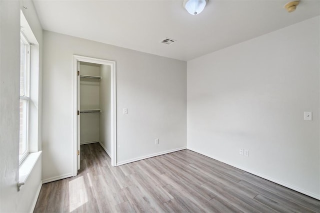 2013 Cedar Meadow Ln, Edmond, OK 73003 - unfurnished bedroom with wood finished floors, multiple windows, a walk in closet, and baseboards