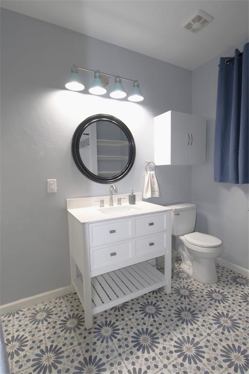 1016 N Louisa Ave, Shawnee, OK 74801 - bathroom with baseboards, toilet, and vanity