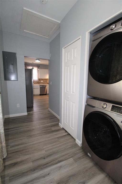 1016 N Louisa Ave, Shawnee, OK 74801 - washroom featuring stacked washer / drying machine, electric panel, attic access, wood finished floors, and baseboards