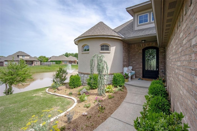 3716 Doningham Dr, Edmond, OK 73034 - entrance to property with a shingled roof, a yard, brick siding, a water view, and stucco siding