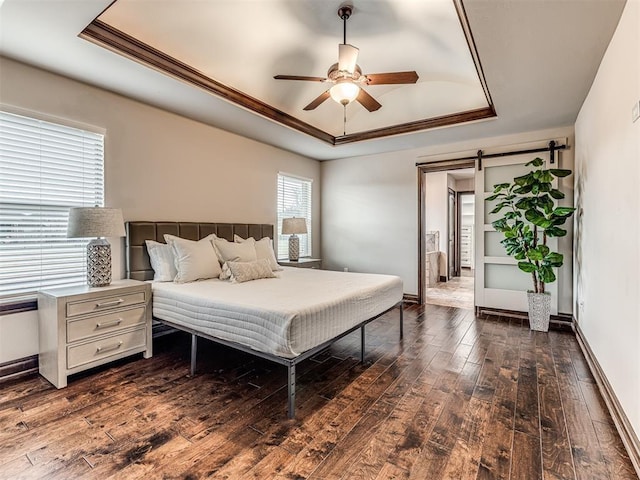 3716 Doningham Dr, Edmond, OK 73034 - bedroom with a tray ceiling, a barn door, dark wood-style flooring, crown molding, and baseboards