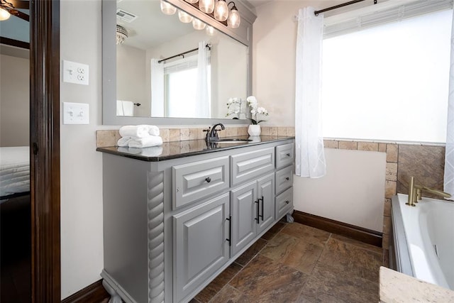 3716 Doningham Dr, Edmond, OK 73034 - bathroom with stone tile flooring, a tub to relax in, vanity, and a wainscoted wall