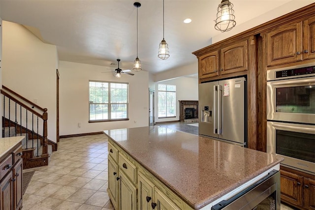 16371 Sandstone Cir, Choctaw, OK 73020 - kitchen with appliances with stainless steel finishes, ceiling fan, open floor plan, a brick fireplace, and dark stone counters