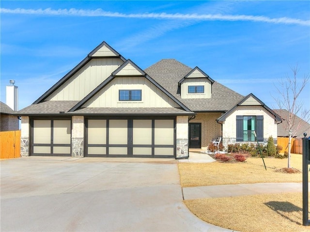 view of front of property with driveway, fence, a shingled roof, board and batten siding, and stone siding