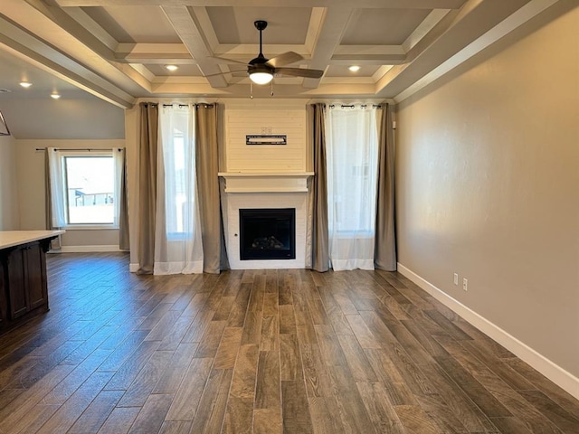unfurnished living room with a ceiling fan, baseboards, dark wood-type flooring, coffered ceiling, and beamed ceiling
