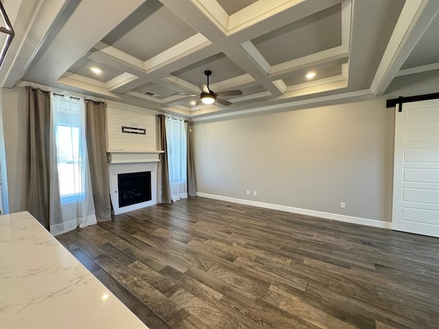 unfurnished living room featuring a barn door, baseboards, a ceiling fan, dark wood-style flooring, and a fireplace