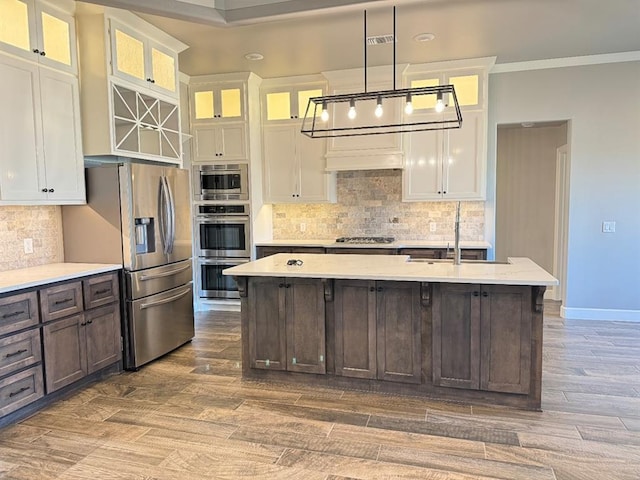 kitchen with a sink, stainless steel appliances, white cabinets, dark brown cabinets, and crown molding