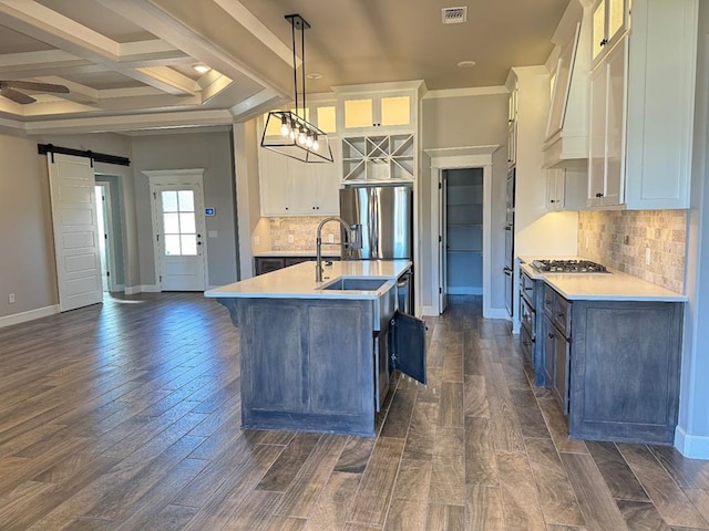 kitchen featuring a barn door, stainless steel gas stovetop, a sink, light countertops, and coffered ceiling