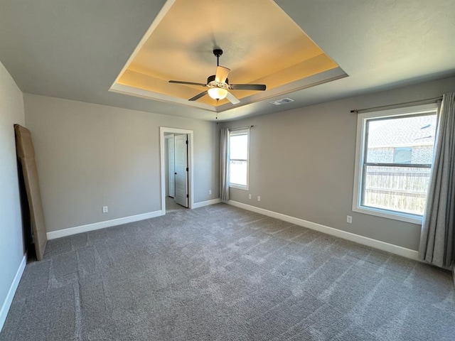 unfurnished room featuring a tray ceiling, baseboards, carpet flooring, and a ceiling fan