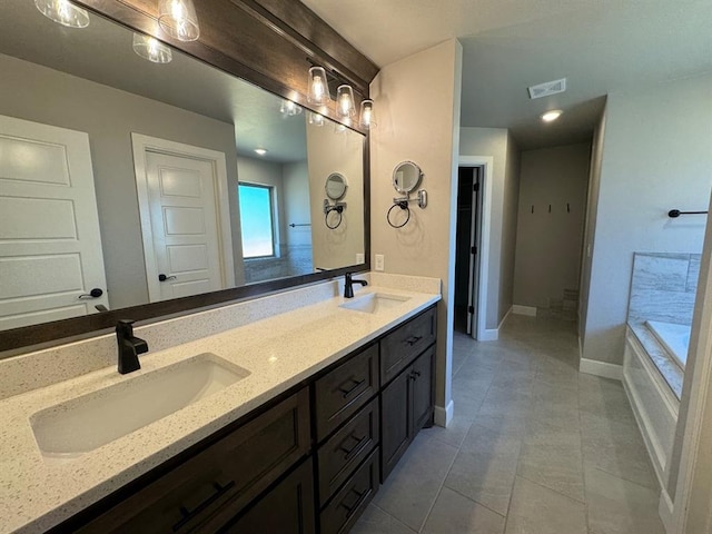 full bathroom featuring tile patterned flooring, double vanity, baseboards, and a tub