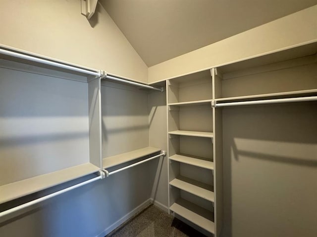 walk in closet featuring lofted ceiling and dark carpet