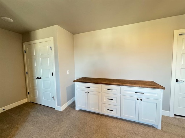 interior space featuring light colored carpet and baseboards