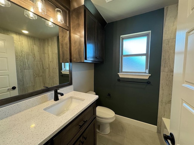 bathroom with toilet, a shower, vanity, and baseboards