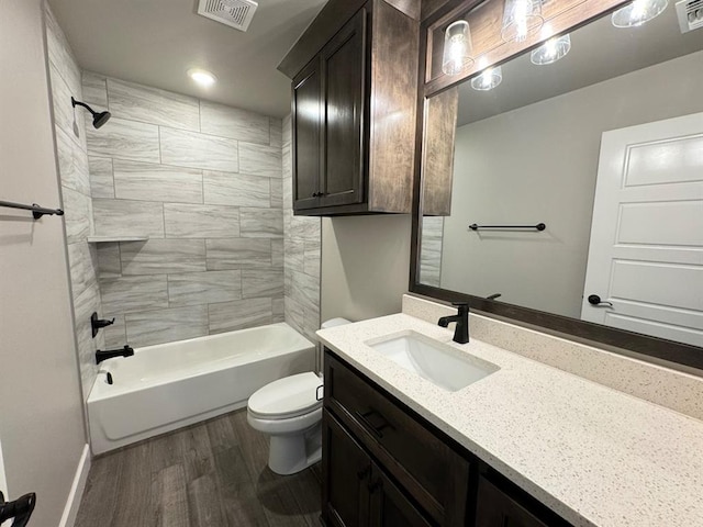 bathroom featuring wood finished floors, toilet, vanity, tub / shower combination, and baseboards