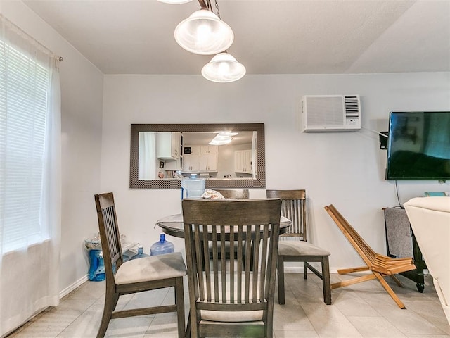 dining room with a wall mounted AC, light tile patterned floors, plenty of natural light, and baseboards