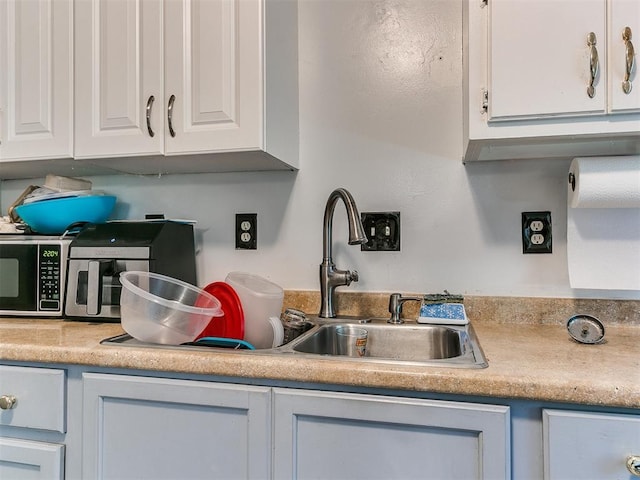 kitchen with white cabinets, light countertops, and a sink