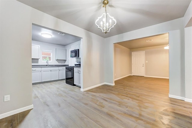 3128 NW 44th St, Oklahoma City, OK 73112 - kitchen featuring black appliances, a chandelier, a sink, and light wood-type flooring