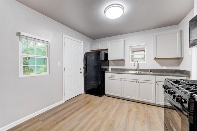 3128 NW 44th St, Oklahoma City, OK 73112 - kitchen featuring black appliances, a sink, light wood finished floors, dark countertops, and white cabinetry