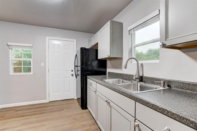 3128 NW 44th St, Oklahoma City, OK 73112 - kitchen with freestanding refrigerator, a sink, dark countertops, light wood-style floors, and white cabinets
