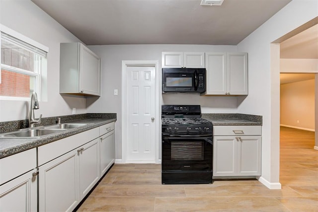 3128 NW 44th St, Oklahoma City, OK 73112 - kitchen featuring black appliances, a sink, light wood-style floors, dark countertops, and baseboards