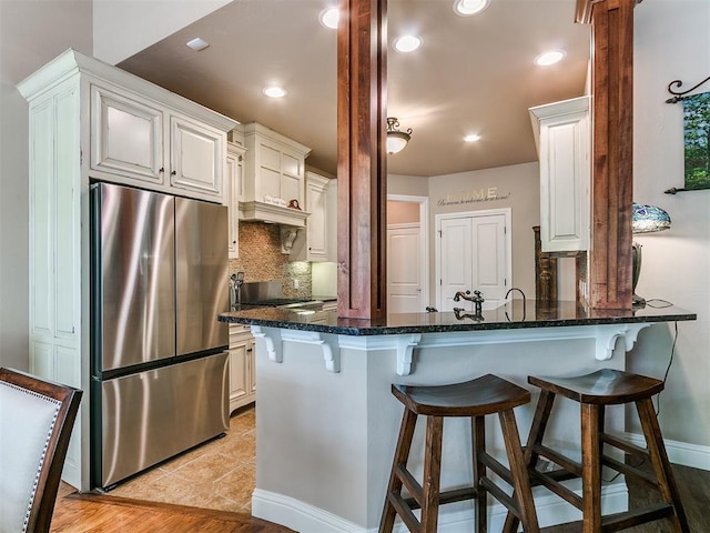 404 Nantucket Blvd, Norman, OK 73071 - kitchen featuring freestanding refrigerator, a peninsula, dark stone countertops, white cabinets, and recessed lighting