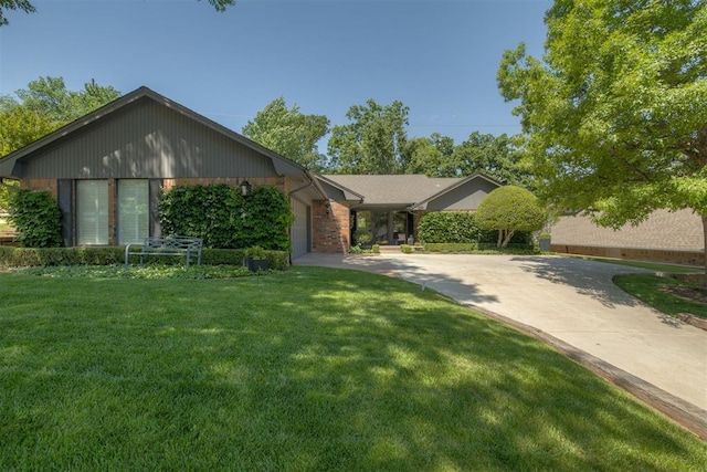 single story home with a front yard, an attached garage, driveway, and brick siding