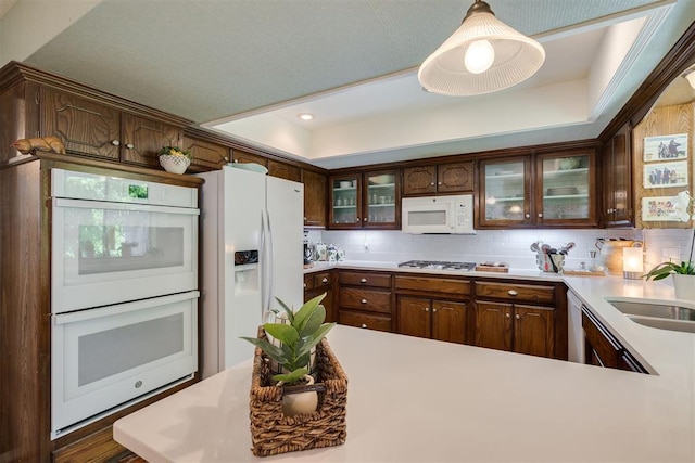 kitchen with white appliances, glass insert cabinets, light countertops, a raised ceiling, and recessed lighting