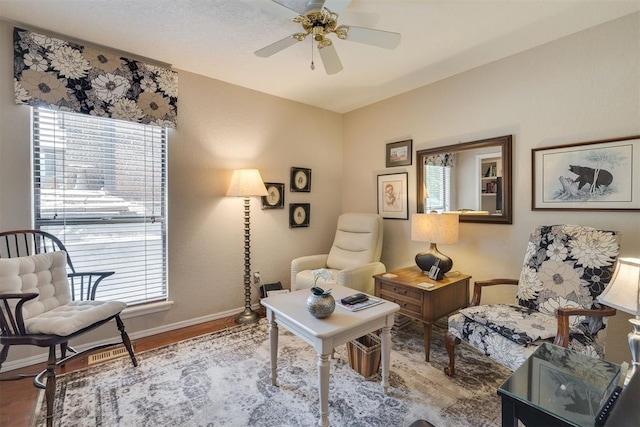 sitting room featuring plenty of natural light, baseboards, a ceiling fan, and wood finished floors