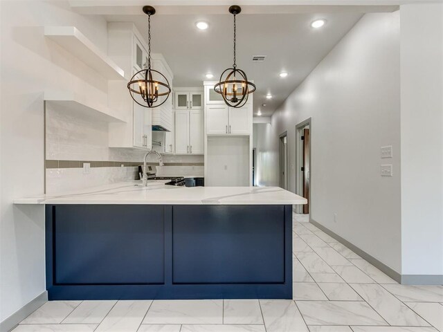 1518 NW 8th St, Oklahoma City, OK 73106 - kitchen with a peninsula, light marble finish floors, a chandelier, a sink, and baseboards