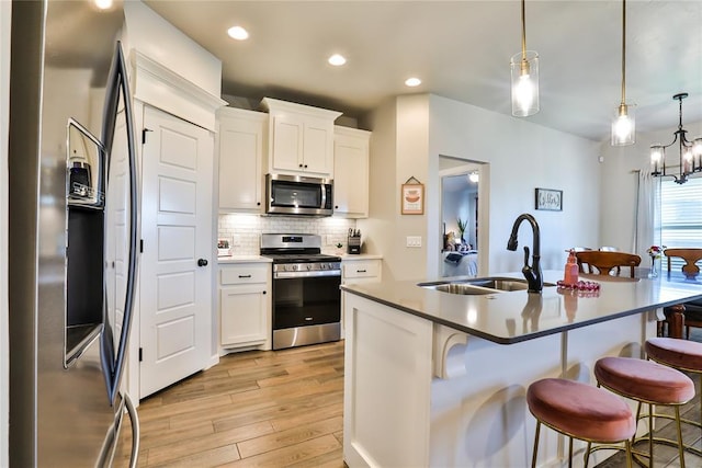 1425 NW 12th St, Newcastle, OK 73065 - kitchen featuring appliances with stainless steel finishes, a sink, light wood-style floors, a kitchen bar, and backsplash