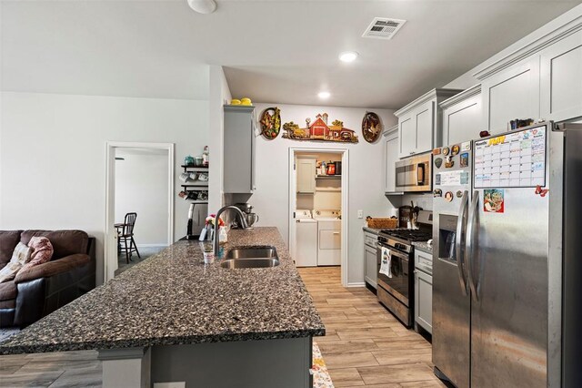 12509 NE 36th Sts, Spencer, OK 73084 - kitchen featuring appliances with stainless steel finishes, a sink, washer and dryer, dark stone counters, and a peninsula