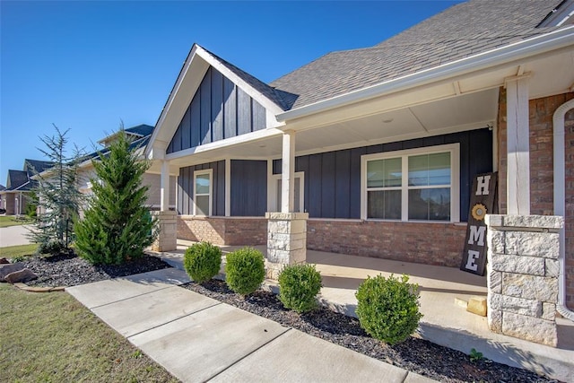 14205 Village Creek Way, Piedmont, OK 73078 - view of exterior entry featuring board and batten siding, brick siding, covered porch, and a shingled roof