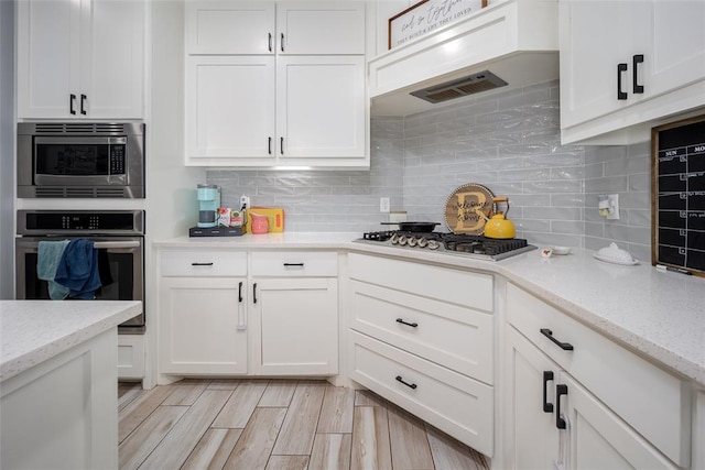 14205 Village Creek Way, Piedmont, OK 73078 - kitchen featuring stainless steel appliances, white cabinetry, and backsplash