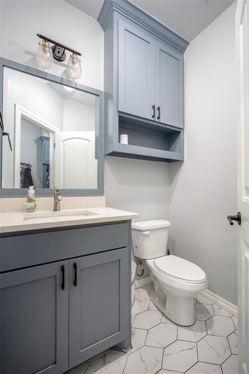 14205 Village Creek Way, Piedmont, OK 73078 - bathroom with marble look tiles, toilet, vanity, and baseboards