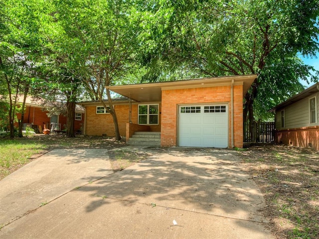 view of front of house with an attached garage, brick siding, concrete driveway, and fence