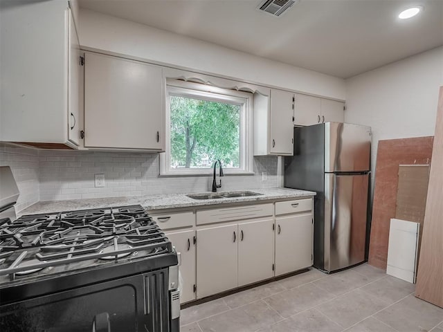 kitchen with a sink, appliances with stainless steel finishes, tasteful backsplash, light tile patterned floors, and light stone countertops