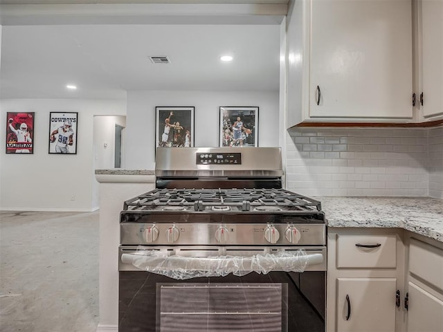 kitchen with stainless steel gas range oven, decorative backsplash, baseboards, recessed lighting, and white cabinets