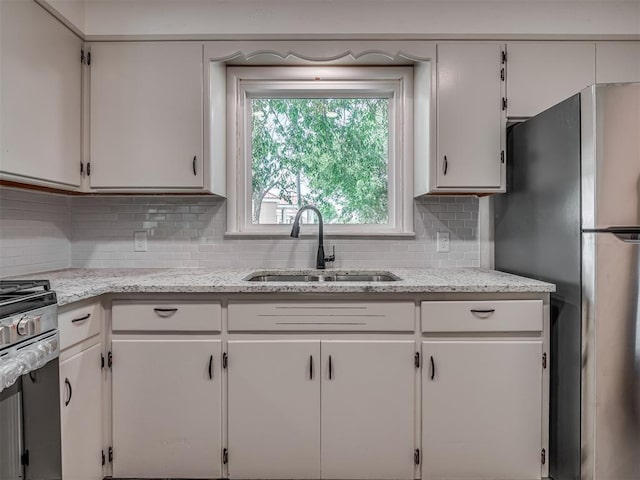 kitchen with a sink, decorative backsplash, and white cabinetry