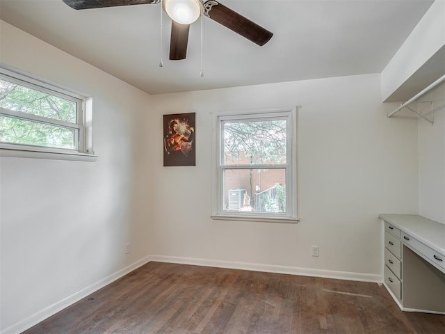 unfurnished office featuring plenty of natural light, a ceiling fan, dark wood-style flooring, and baseboards