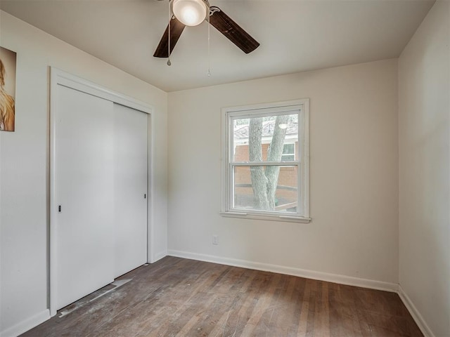 unfurnished bedroom featuring wood finished floors, a closet, baseboards, and a ceiling fan