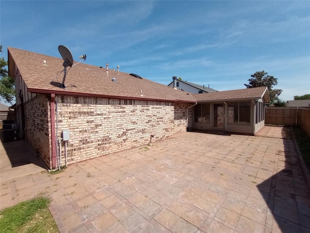 11209 Cimarron Dr, Oklahoma City, OK 73162 - back of house with a patio, a sunroom, brick siding, a fenced backyard, and roof with shingles