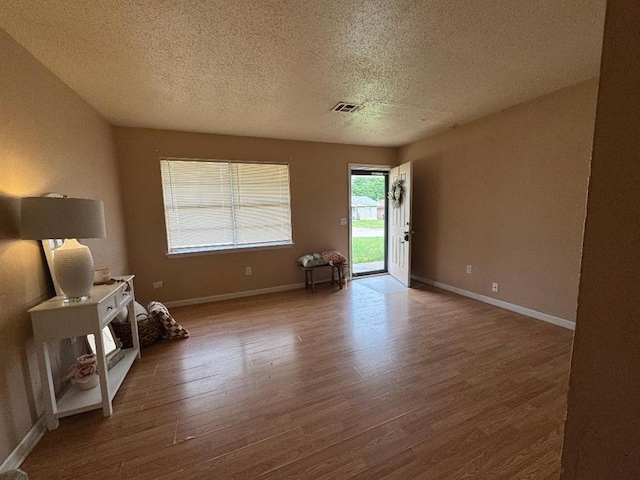 living area with a textured ceiling, wood finished floors, and baseboards