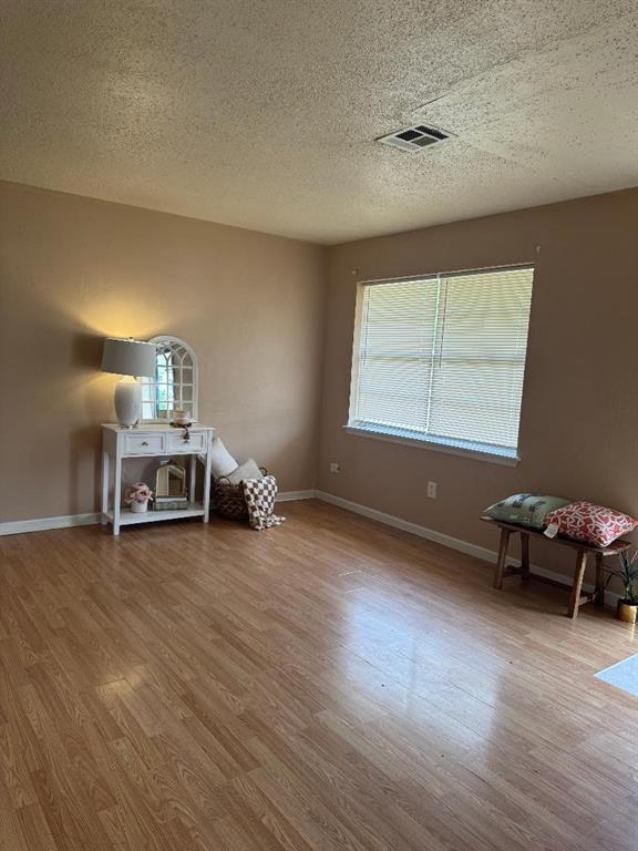 unfurnished room featuring a textured ceiling, wood finished floors, and baseboards
