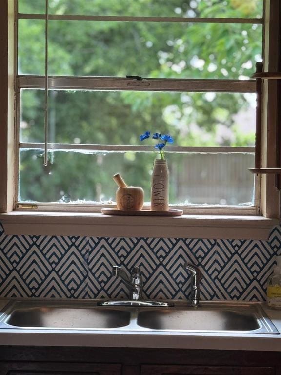detailed view of pot filler, a sink, and backsplash