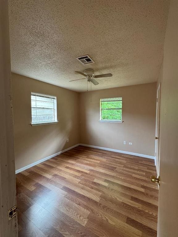 spare room featuring a textured ceiling, wood finished floors, ceiling fan, and baseboards