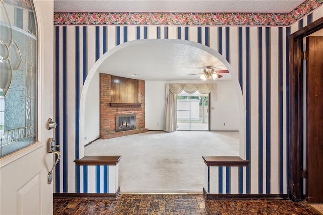 3109 N Glade Ave, Bethany, OK 73008 - carpeted entrance foyer featuring ceiling fan, a brick fireplace, arched walkways, baseboards, and a textured ceiling