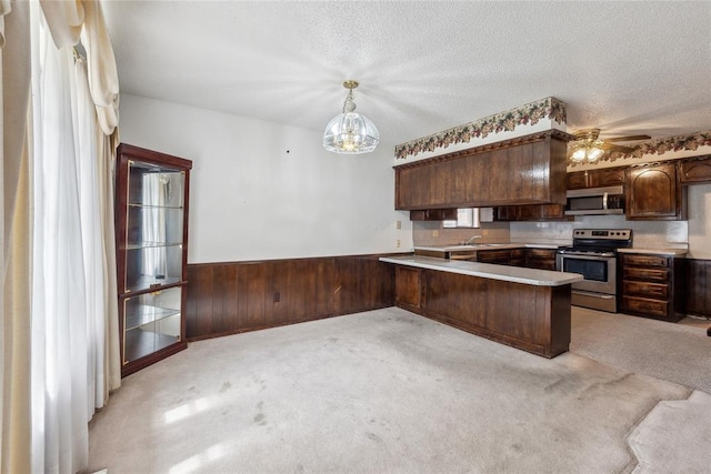 3109 N Glade Ave, Bethany, OK 73008 - kitchen featuring appliances with stainless steel finishes, a peninsula, wainscoting, light carpet, and dark brown cabinetry