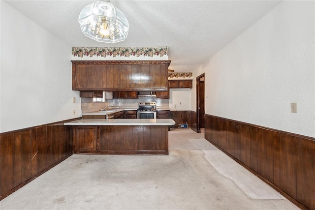 3109 N Glade Ave, Bethany, OK 73008 - kitchen featuring stainless steel electric range, a peninsula, a wainscoted wall, wood walls, and light colored carpet